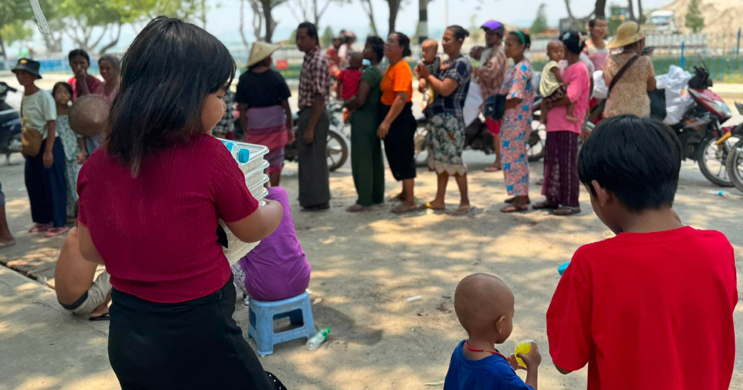 A group of women in Myanmar engaged in a discussion, smiling and supporting each other in a community setting, symbolizing resilience and collective rebuilding efforts.